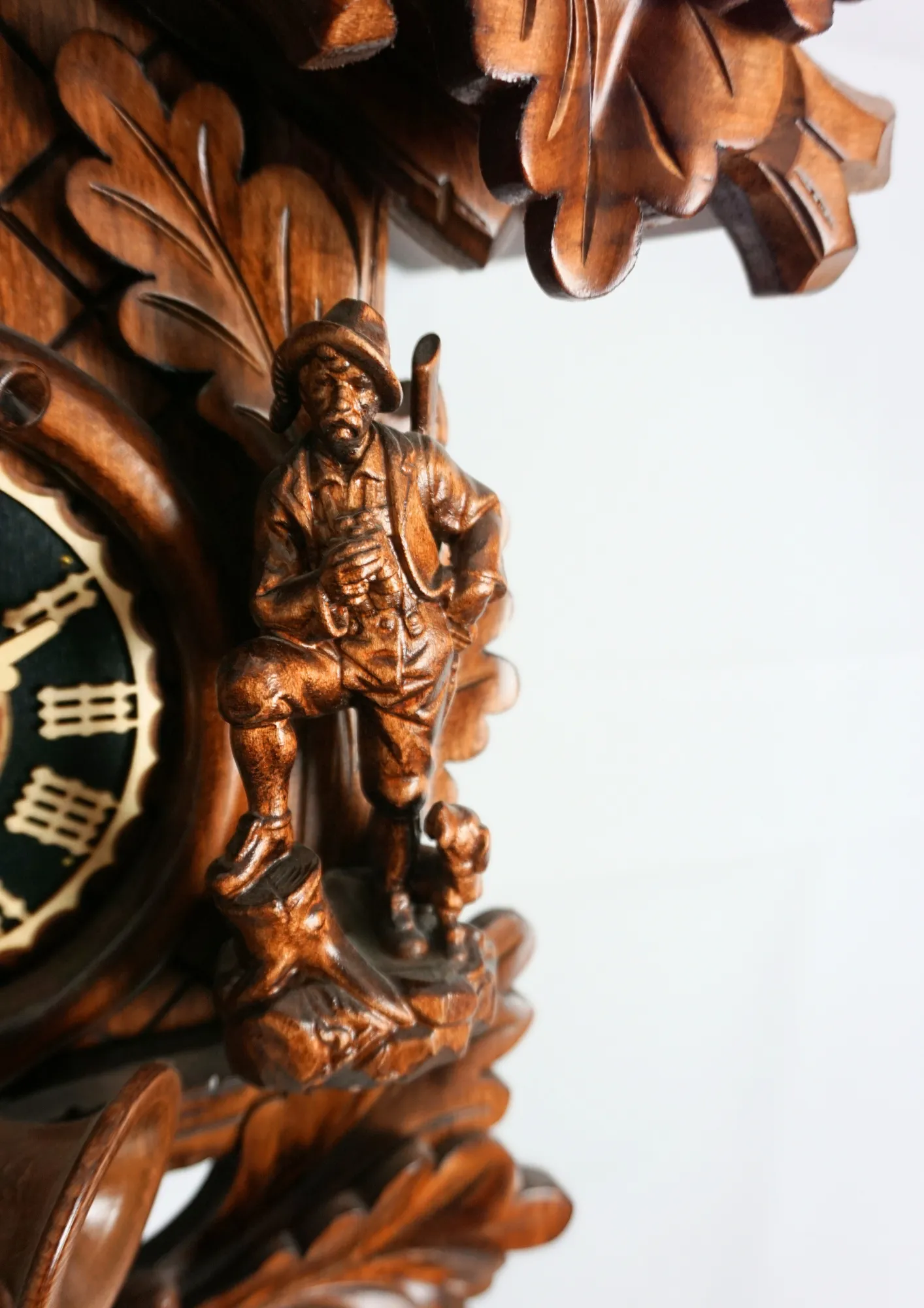 Hand carved authentic mechanical brown black forest cuckoo clock in a hunter theme. Precisely carved deer head is decorating the top while there is a hunter and a falcon figure on the sides of the clock. The clocks dial is wraped with a hunting horn while