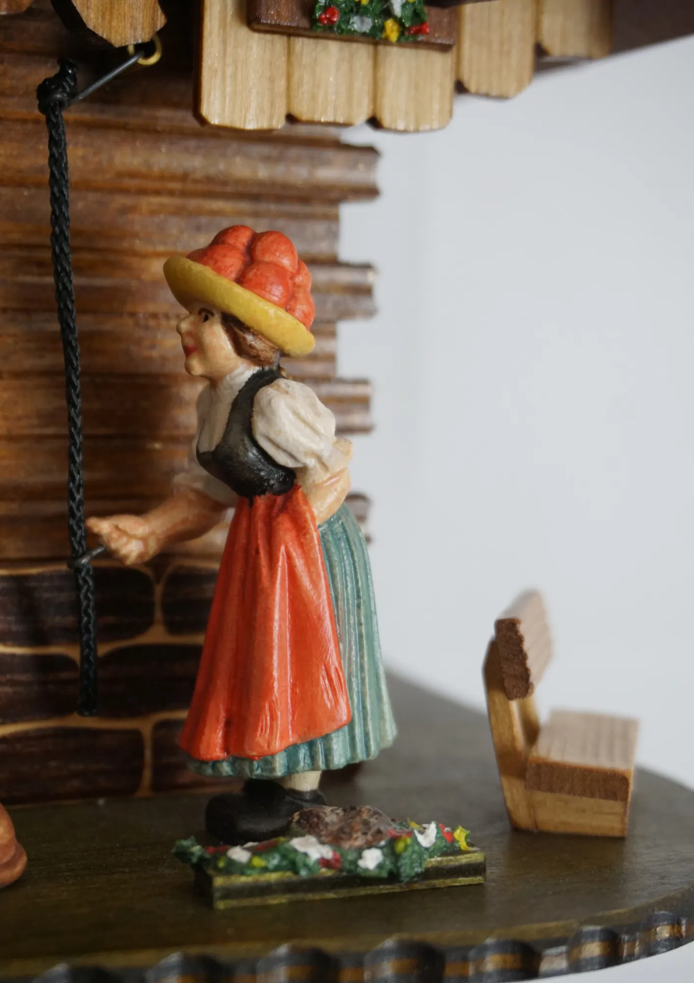 Cuckoo Clock Bell Ringer Small 1 Day Movement with Music (3) Chalet style authentic mechanical black forest cuckoo clock with shingle roof, church tower bell and black forest lady wearing traditional clothing, the lady rings the bell together with the cuckoo sound, music plays and water wheel turns. This clock has
