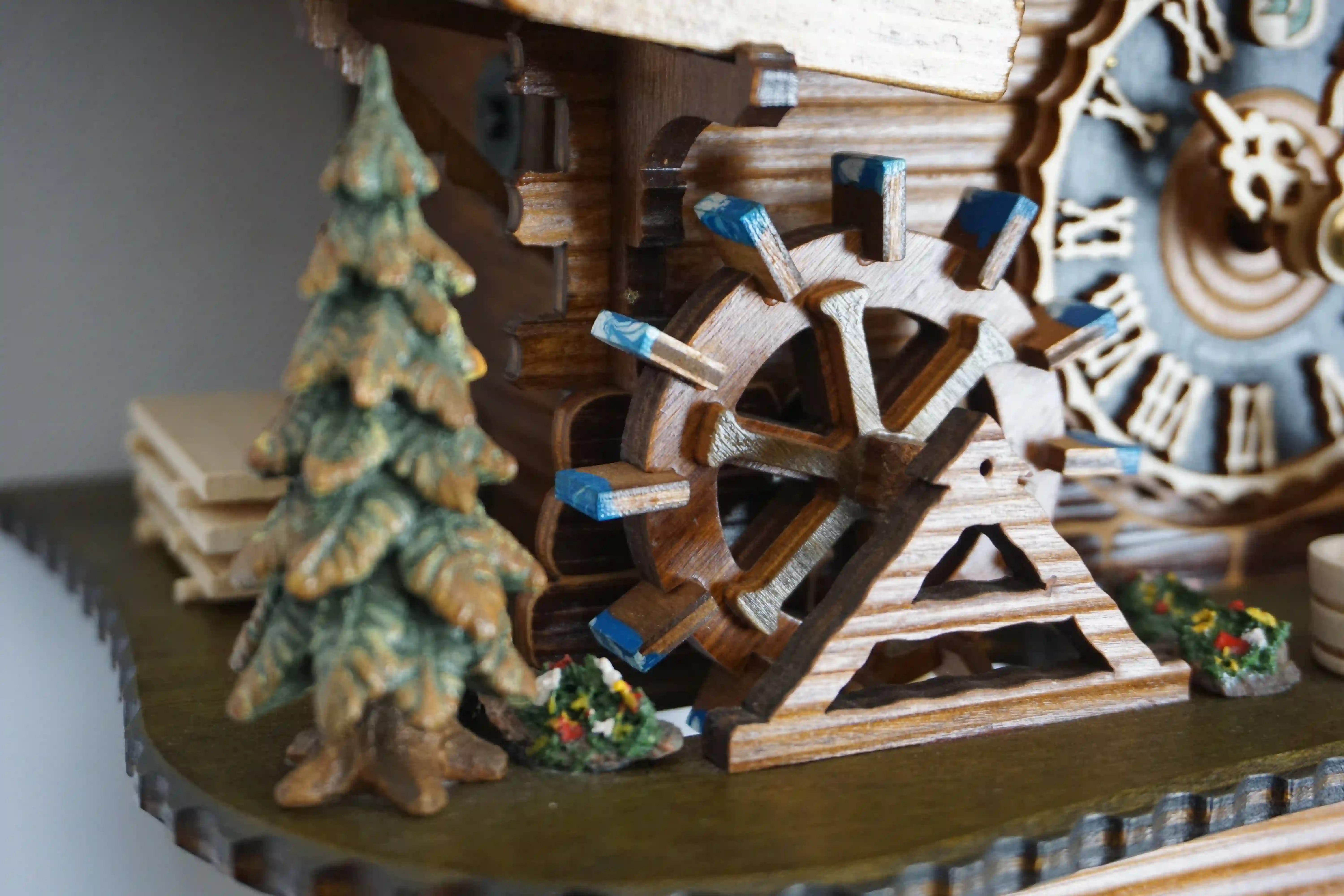 Cuckoo Clock Bell Ringer Small 1 Day Movement with Music (6) Chalet style authentic mechanical black forest cuckoo clock with shingle roof, church tower bell and black forest lady wearing traditional clothing, the lady rings the bell together with the cuckoo sound, music plays and water wheel turns. This clock has