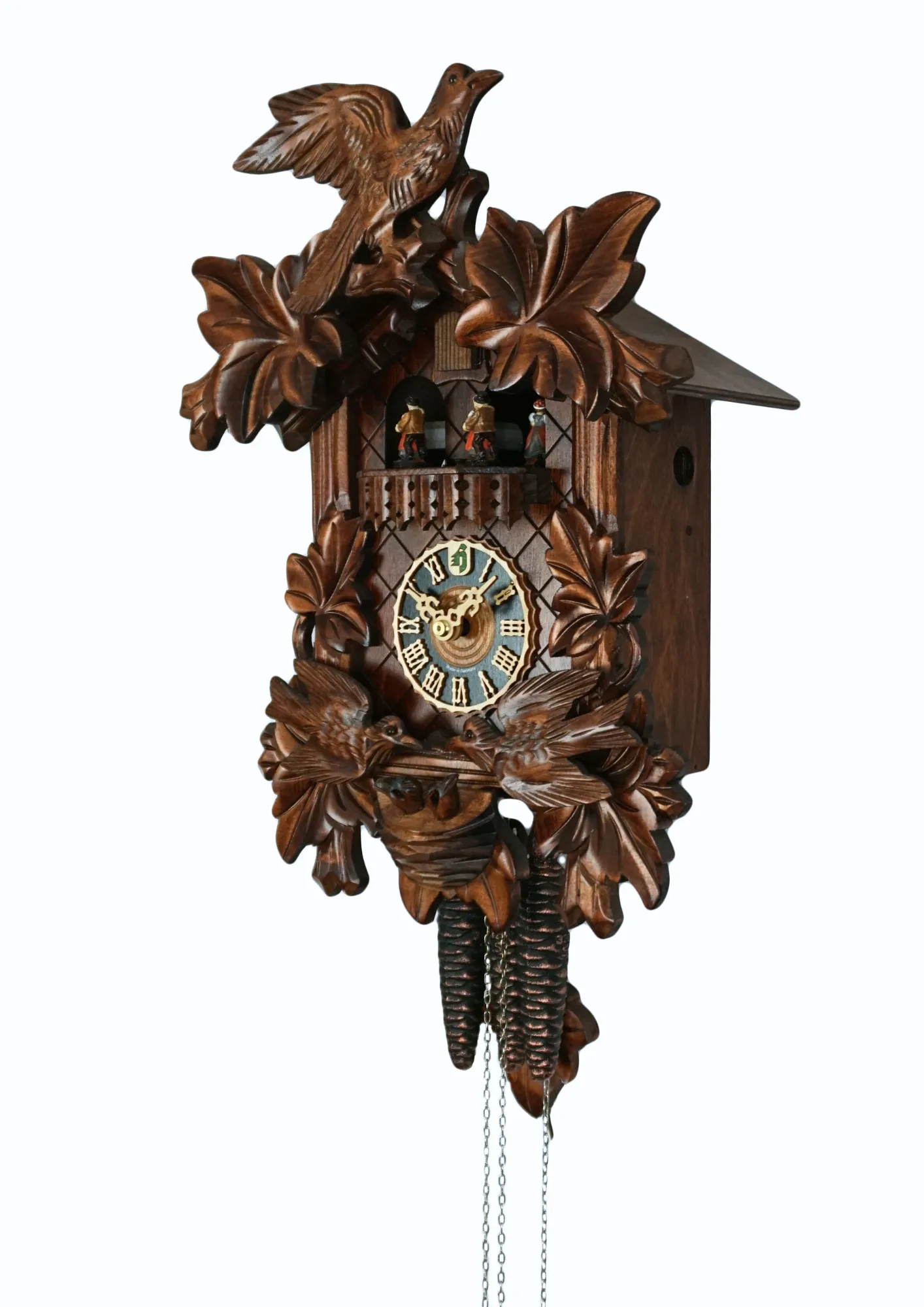 Traditional hand carved black forest mechanical cuckoo clock with music, decorated with two birds moving and feeding the offspring in the nest, dancers dance with music