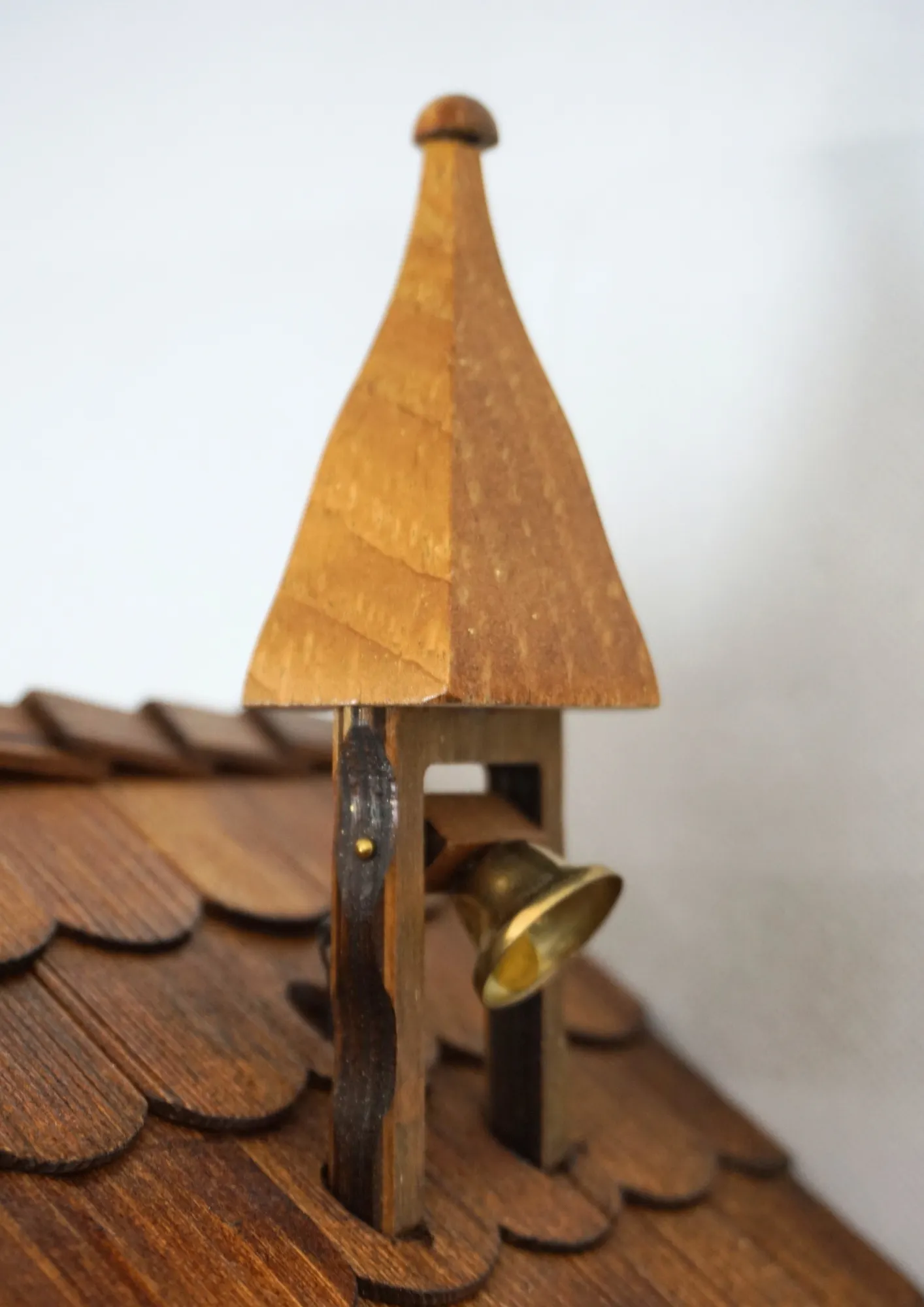 Cuckoo Clock Bell Ringer Small 1 Day Movement with Music (4) Chalet style authentic mechanical black forest cuckoo clock with shingle roof, church tower bell and black forest lady wearing traditional clothing, the lady rings the bell together with the cuckoo sound, music plays and water wheel turns. This clock has